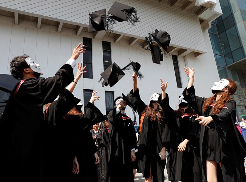 Graduates wearing Guy Fawkes masks throw their hats as they pose for their photo after a graduation ceremony at the Chinese University of Hong Kong in Hong Kong, China, November 7, 2019. Photo: Reuters
