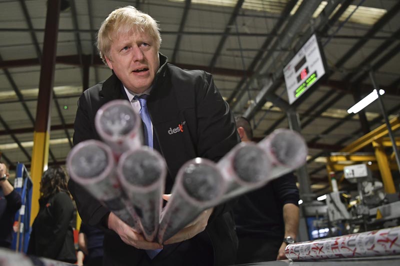 Britain's Prime Minister Boris Johnson, centre, gestures with Christmas wrapping paper, during a visit to IG Design Group, wrapping paper designer and producer in Hengoed, south Wales, Wednesday, December 11, 2019 on the final day of campaigning for the general election. Photo: Ben Stansall/Pool Photo via AP