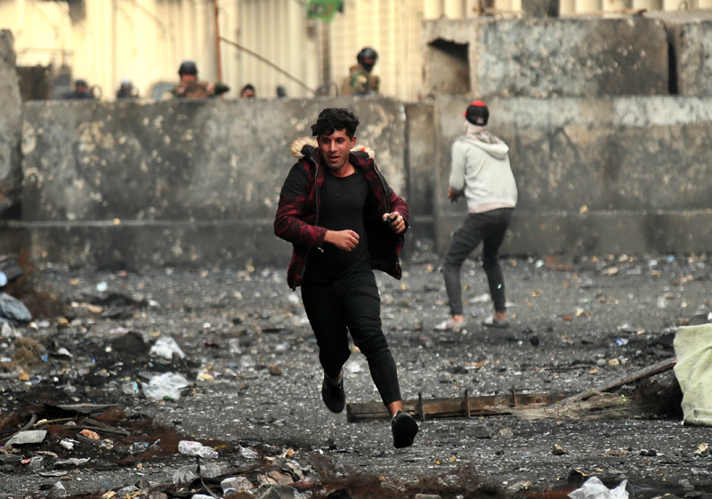 Anti-government protesters throw stones while security forces close Rasheed Street during clashes in Baghdad, Iraq, Friday, Dec 6, 2019. Photo: AP