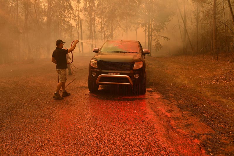 A local man hoses down fire retardant during a bushfire in Werombi, 50 km southwest of Sydney, Australia, December 6, 2019. Photo: Reuters