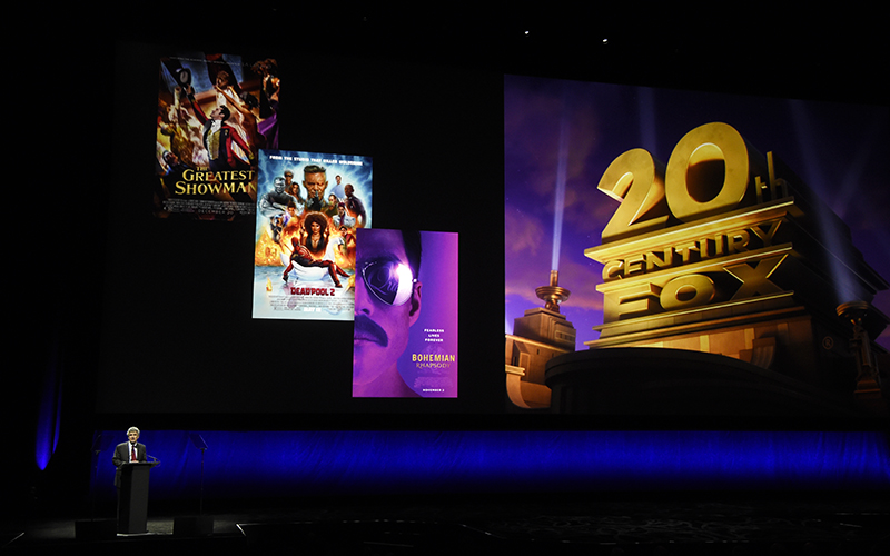 Alan Horn, chairman of The Walt Disney Studios, speaks underneath poster images for 20th Century Fox films during the Walt Disney Studios Motion Pictures presentation at CinemaCon 2019, the official convention of the National Association of Theatre Owners (NATO) at Caesars Palace in Las Vegas, April 3, 2019. Photo by Chris Pizzello/Invision via AP/File