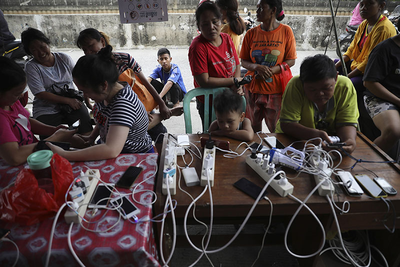 People check their phones at a charging station for those affected by floods in Jakarta, Indonesia, Saturday, Jan. 4, 2020. Photo: AP