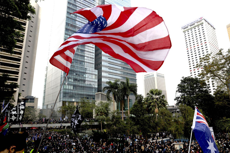 A participant waves a U.S. flag as a colonial flag is seen on right during a rally demanding electoral democracy and call for boycott of the Chinese Communist Party and all businesses seen to support it in Hong Kong, Sunday, Jan. 19, 2020. Photo: AP