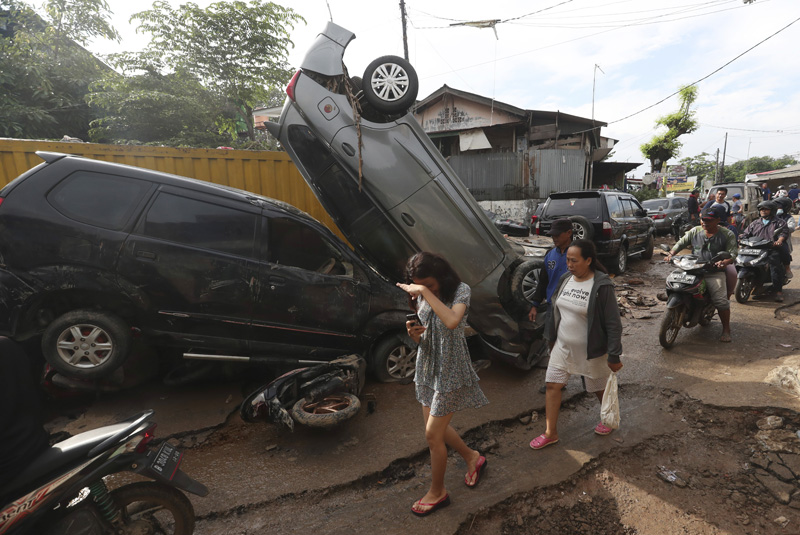 Residents walk near the wreckage of cars that were swept away by flood in Bekasi, West Java, Indonesia, Friday, Jan 3, 2020. Photo: AP