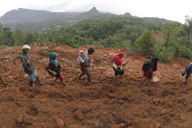 FILE - Villagers make their way at an area affected by a landslide in Sukajaya, West Java, Indonesia, Sunday, Jan 5, 2020. Photo: AP