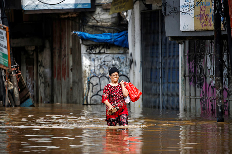 A woman carries her belongings across floodwaters in the Jatinegara area after heavy rains in Jakarta, Indonesia, on January 2, 2020. Photo: Reuters