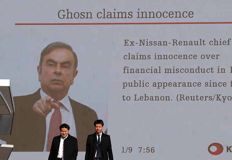 Passersby walk in front of a huge street monitor reporting a news conference by former Nissan chairman Carlos Ghosn in Beirut, in Tokyo, Japan, January 9, 2020.  Photo: Reuters