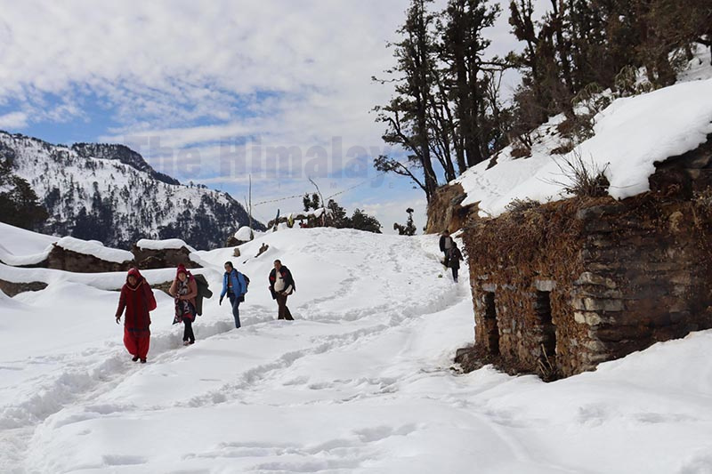 Locals walking along a snow-covered road, in Kolti bazaar, Bajura, on Saturday. Snow has blanketed most high hilly districts in the far-western region. Photo: Prakash Singh/ THT