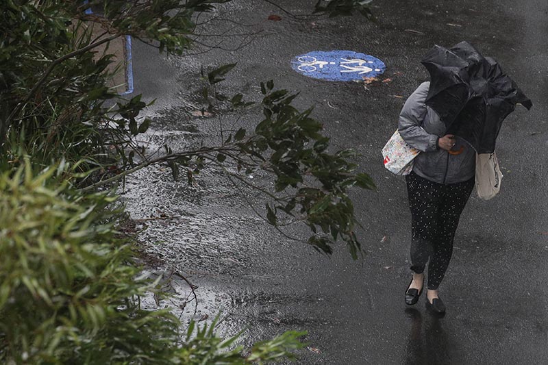 A pedestrian braves strong wind and rain in Sydney, New South Wales, Australia, February 9, 2020. Photo: Reuters