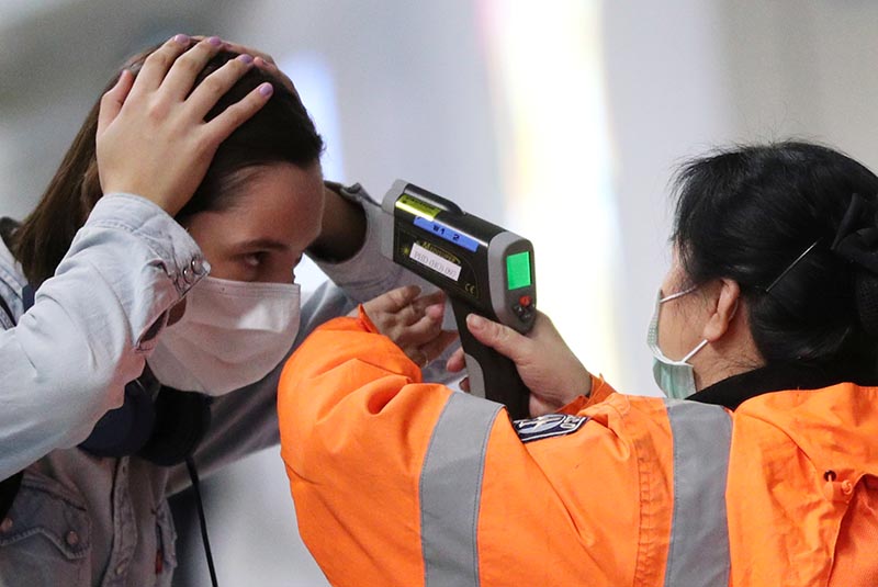 A worker checks the temperature of a passenger arriving into Hong Kong International Airport with an infrared thermometer, following the coronavirus outbreak in Hong Kong, China, February 7, 2020. Photo: Reuters