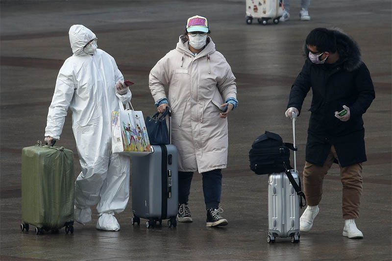 A passenger wearing a full-body protective suit catches the eyes of others as they walk out from the Beijing railway station in Beijing, Tuesday, February, 11, 2020. Photo: AP