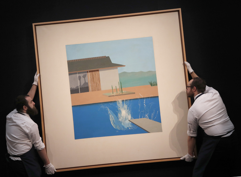 Two Sotheby's employees adjust David Hockney's painting 'The Splash' at Sotheby's contemporary Art sale preview in London, Friday, Feb 7, 2020. Photo: AP