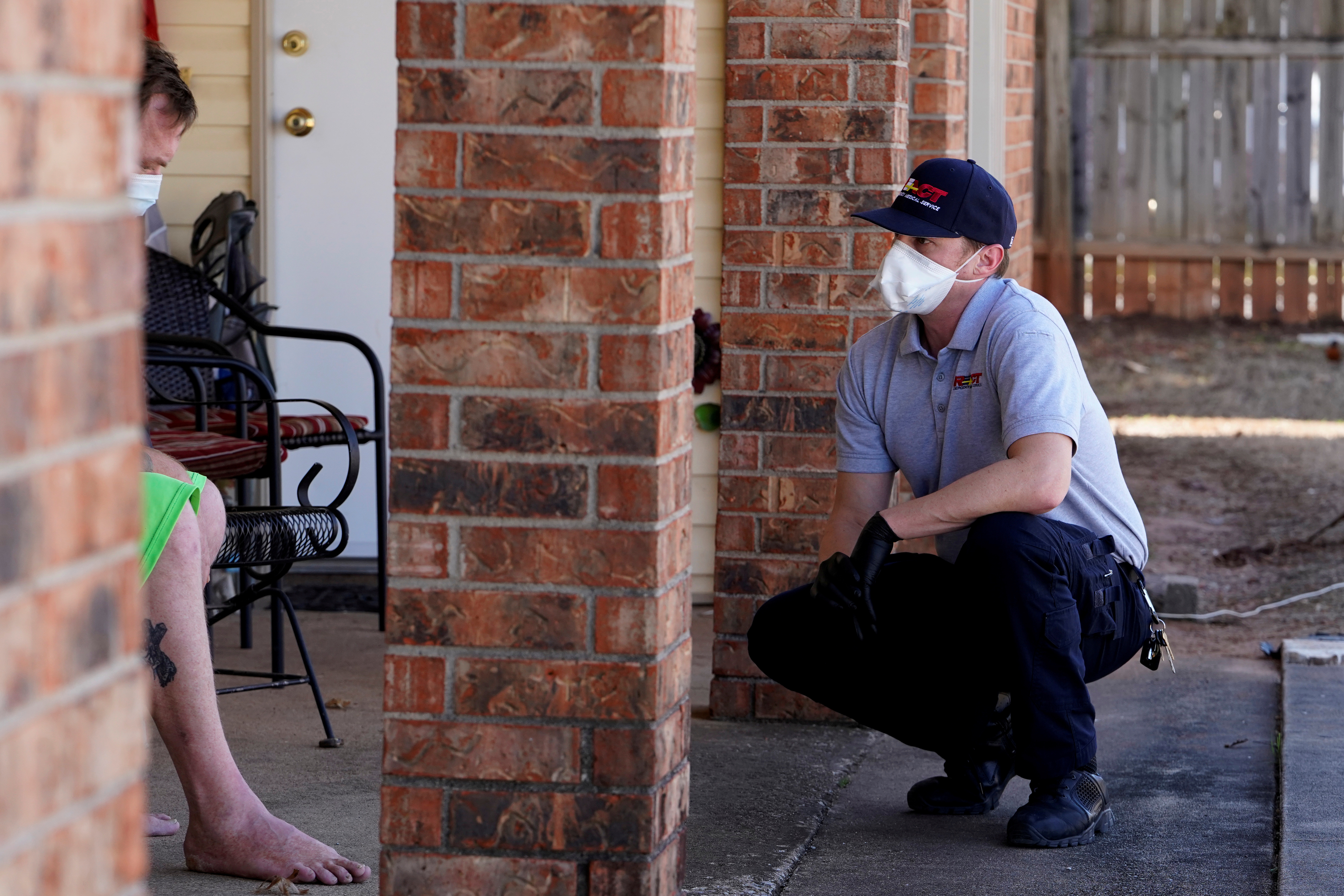 REACT EMS paramedic Brian Myers wears a protective mask and gloves as he squats near a potential coronavirus disease (COVID-19) patient in Shawnee, Oklahoma, U.S. March, on 26, 2020. Photo: Reuters