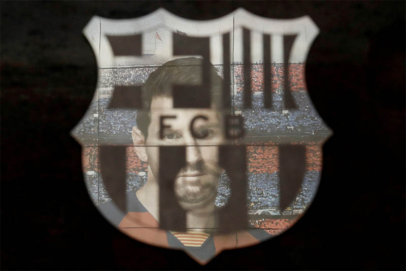 FILE PHOTO: A picture of Lionel Messi is reflected in the Barcelona emblem outside the stadium before the match. Photo: Reuters