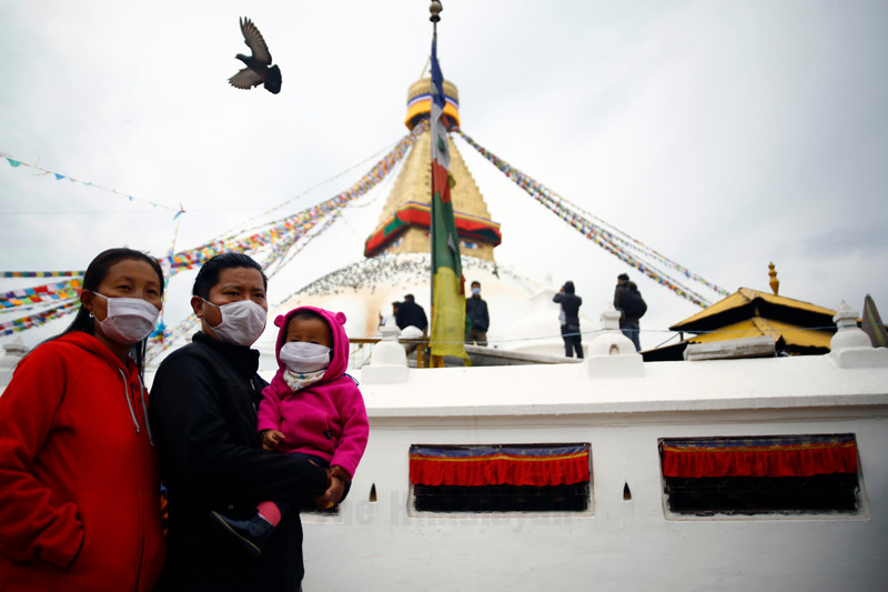 Members of a family, wearing face masks amid coronavirus fear, listen to prayers by Buddhist nuns, at Bouddhanath Stupa, in Kathmandu, on Saturday, March 14, 2020. Photo: Skanda Gautam/THT