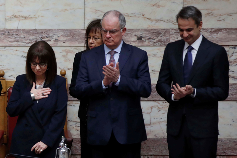 Newly elected Greek President Katerina Sakellaropoulou, gestures as Greece's Prime Minister Kyriakos Mitsotakis and Spokesman of the Greek Parliament Konstantinos Tasoulas, applaud during the swearing-in ceremony at the parliament in Athens, Greece March 13, 2020. Photo: Thanassis Stavrakis/Pool via Reuters