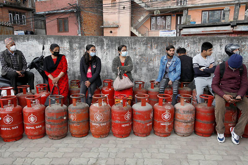 People sit on top of empty cooking gas cylinders, waiting to buy the gas, amid fears of scarcity due to coronavirus disease (COVID-19) outbreak, in Kathmandu, Nepal March 23, 2020. Photo: Reuters