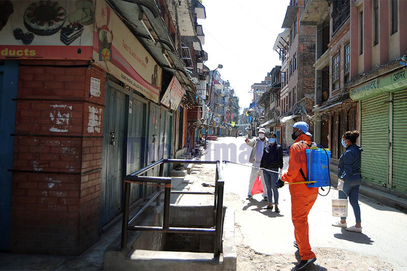 A municipal worker disinfects a pavement at Mangalbazaar area during a 14-day nationwide lockdown to limit the spreading of COVID-19 which causes respiratory illness due to coronavirus, in Lalitpur, on Monday, March 30, 2020. Photo: Balkrishna Thapa Chhetri/THT