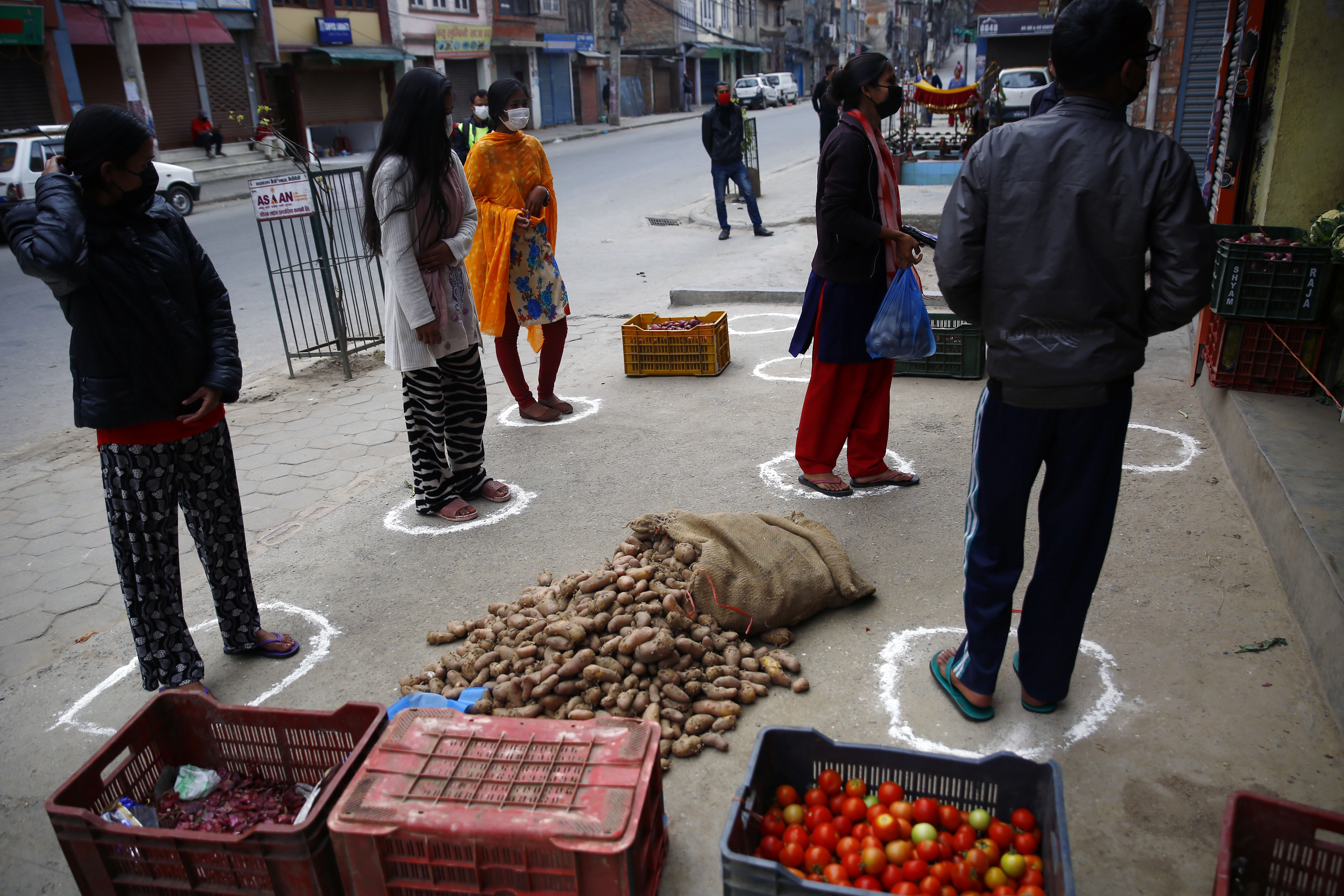 People stand on markings while buying vegetables to maintain physical distance on the fourth day of government-imposed lockdown, amid concerns over the spread of coronavirus, outside a vegetable-shop, in Kathmandu, on Friday, March 27, 2020. Photo: Skanda Gautam/THT