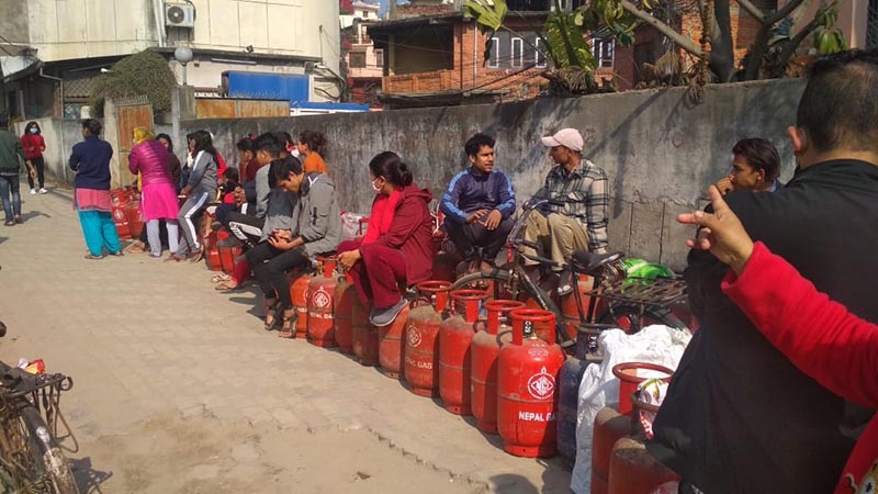 Consumers sitting on LPG cylinders and waiting for their turn in a queue to purchase the cooking gas at a retail store in Anamnagar, Kathmandu, on Friday, March 6, 2020. The assurance by traders and government officials that there is sufficient stock of essential goods has not dissuaded consumers from panic buying. Photo: Suresh Chaudhary/THT