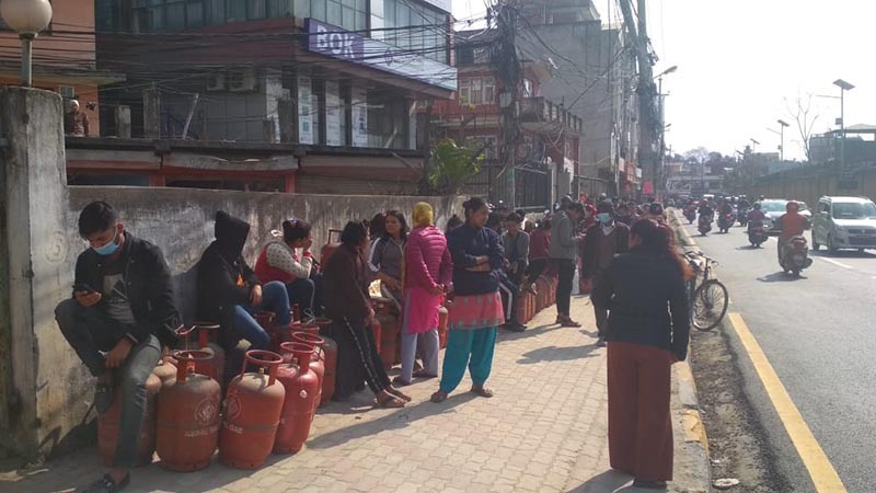 Consumers sitting on LPG cylinders and waiting for their turn in a queue to purchase the cooking gas at a retail store in Anamnagar, Kathmandu, on Friday, March 6, 2020. Photo: Suresh Chaudhary/THT