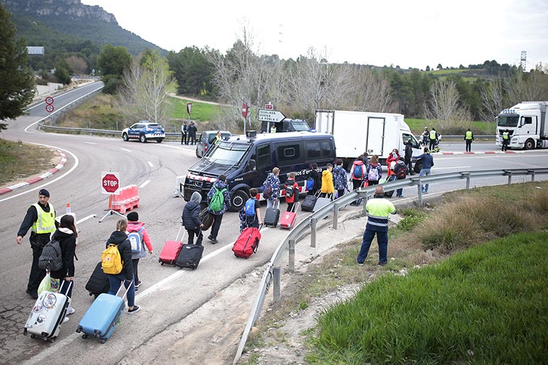 School children returning from a trip walk to change buses on a closed off road after being allowed to enter Igualada, Spain, on Friday, March 13, 2020. Over 60,000 people awoke Friday in four towns near Barcelona confined to their homes and with police blocking roads. Photo: AP