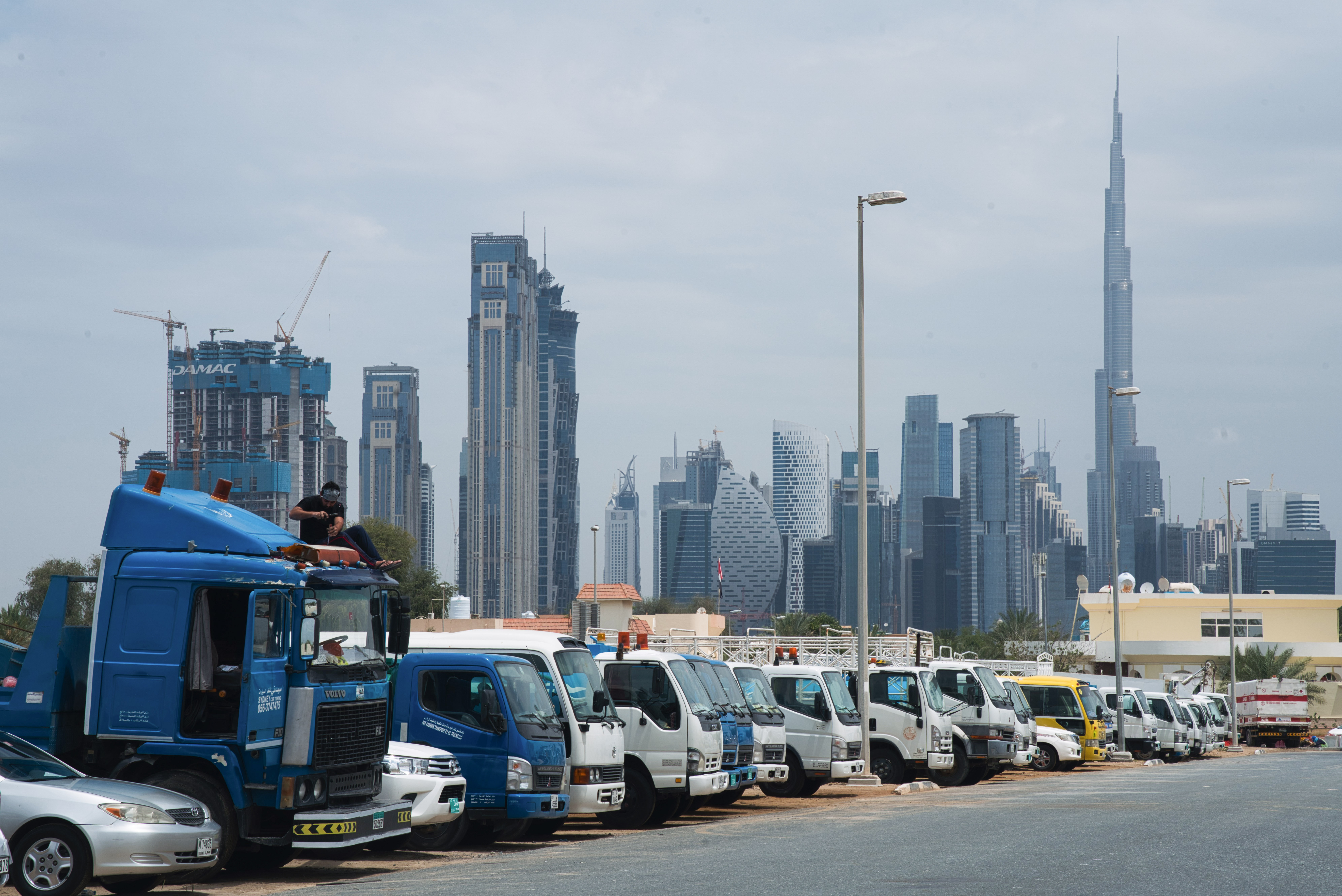 In this Thursday, April 16, 2020 photo, a truck driver works on the cab of his vehicle as Dubai's skyscrapers loom in the background, in Dubai, United Arab Emirates. Migrant workers in oil-rich Gulf Arab states find themselves trapped by the coronavirus pandemic. They are losing jobs, running out of money and desperate to return home as the coronavirus, stalks their labor camps. An unknown number of workers have contracted the virus or have suddenly been forced into mass quarantines, leaving them exposed and painfully vulnerable with little recourse for help. Photo: AP