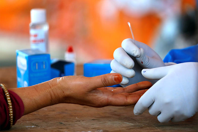 A health worker in a protective gear takes a blood sample from a woman at the makeshift rapid testing centre for the coronavirus disease (COVID-19), in Lalitpur, on April 14, 2020. Photo: Reuters