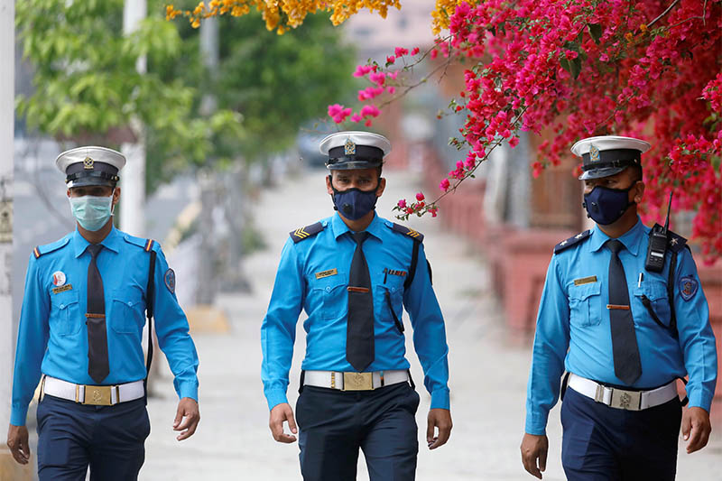 Traffic police personnel wearing protective masks walk along a deserted street as flowers bloom upon the arrival of spring during the twenty-second day of the lockdown imposed by the government amid concerns of the spread of the coronavirus disease (COVID-19), in Kathmandu, on Tuesday,l April 14, 2020. Photo: Reutes