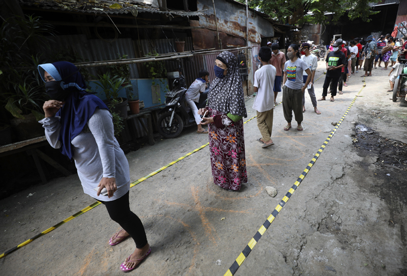 Residents practice social distancing as they queue for donated food during the coronavirus pandemic in a slum area in Jakarta, Indonesia, Wednesday, April 22, 2020. Photo: AP