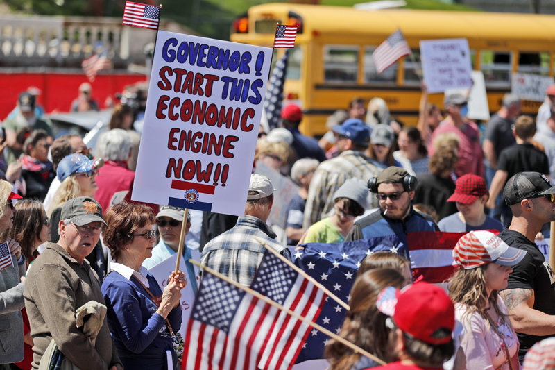 A woman holds a sign as she attends a rally outside the Missouri Capitol to protests stay-at-home orders put into place due to the COVID-19 outbreak Tuesday, April 21, 2020, in Jefferson City, Missouri. Photo: AP