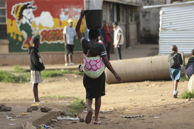 A woman carries a her baby and a bucket of water in Harare, Monday, April 6, 2020. Photo: AP