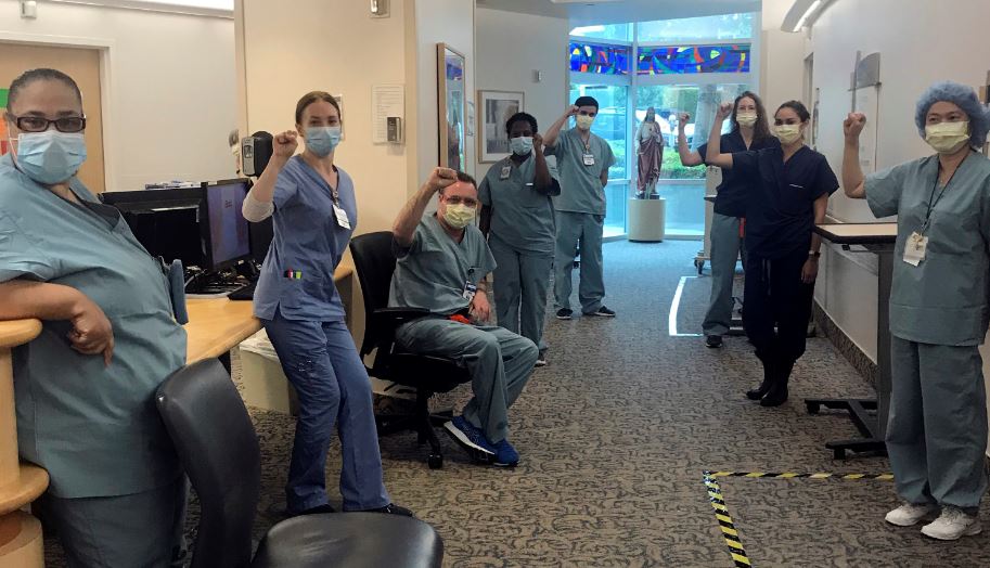 In this image provided by Lizabeth Baker Wade, nurses at Providence Saint John's Health Center in Santa Monica, Calif., on April 10, 2020, raise their fists in solidarity after telling managers they can't care for COVID-19 patients without N95 respirator masks to protect themselves. The hospital has suspended ten nurses from the ward, but has started providing nurses caring for COVID-19 patients with N95 masks. Photo: AP