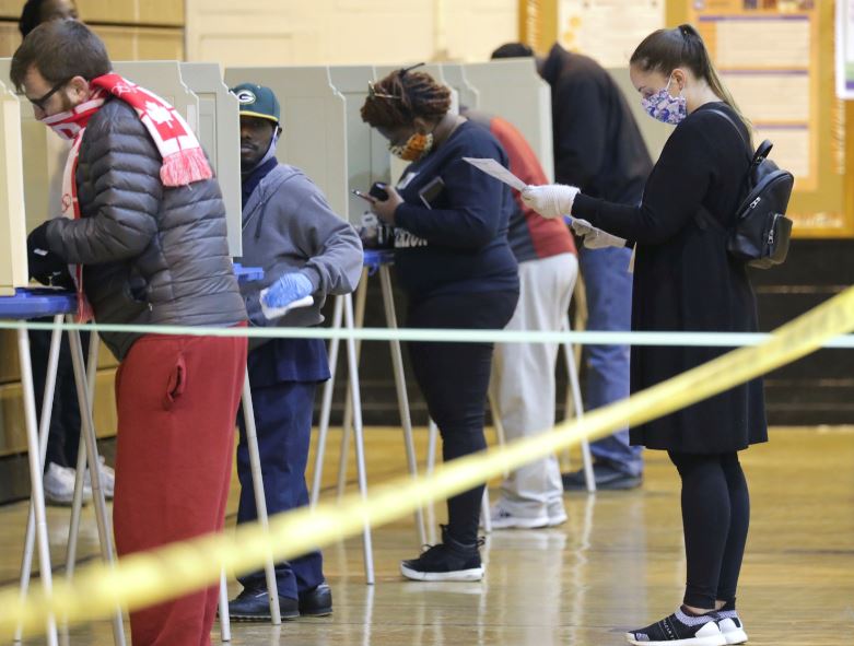 An election official cleans a voting booth before a person votes at Riverside High School, in Milwaukee on Tuesday, April 7, 2020. The Wisconsin primary is moving forward in the wake of the coronavirus epidemic after Gov. Tony Evers sought to shut down Tuesday's election in a historic move Monday that was swiftly rejected by the conservative majority of the Wisconsin Supreme Court by the end of the day. Photo: AP