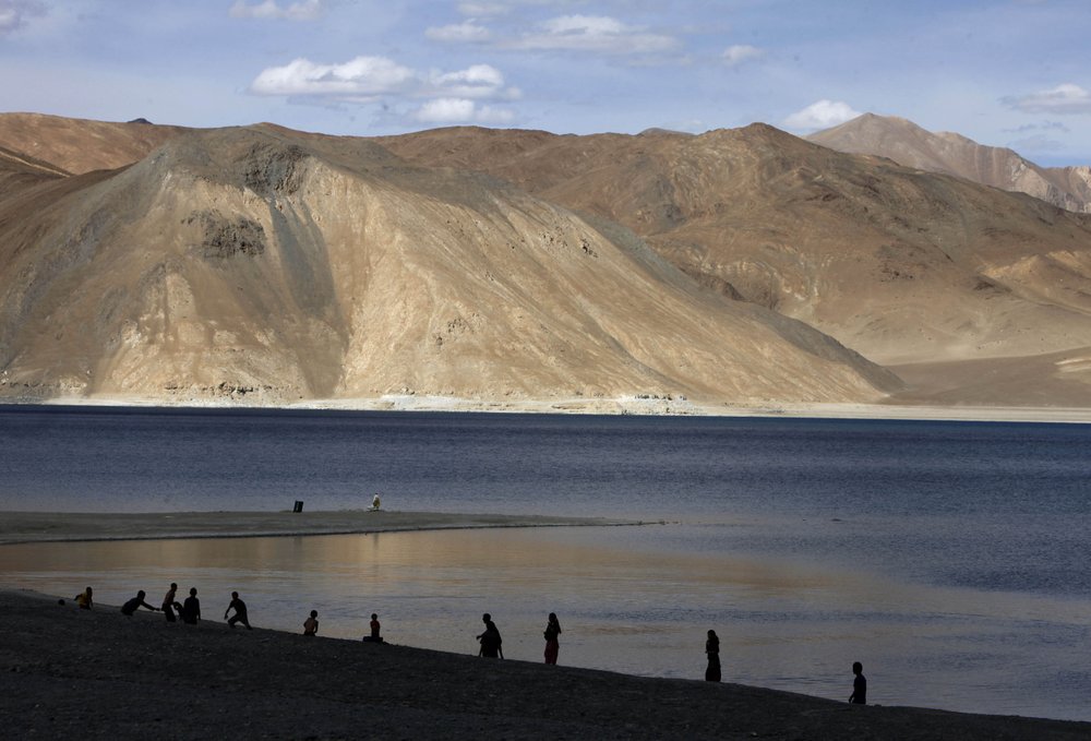 File: People stand by the banks of the Pangong Lake, near the India-China border in Ladakh, India. Photo: AP