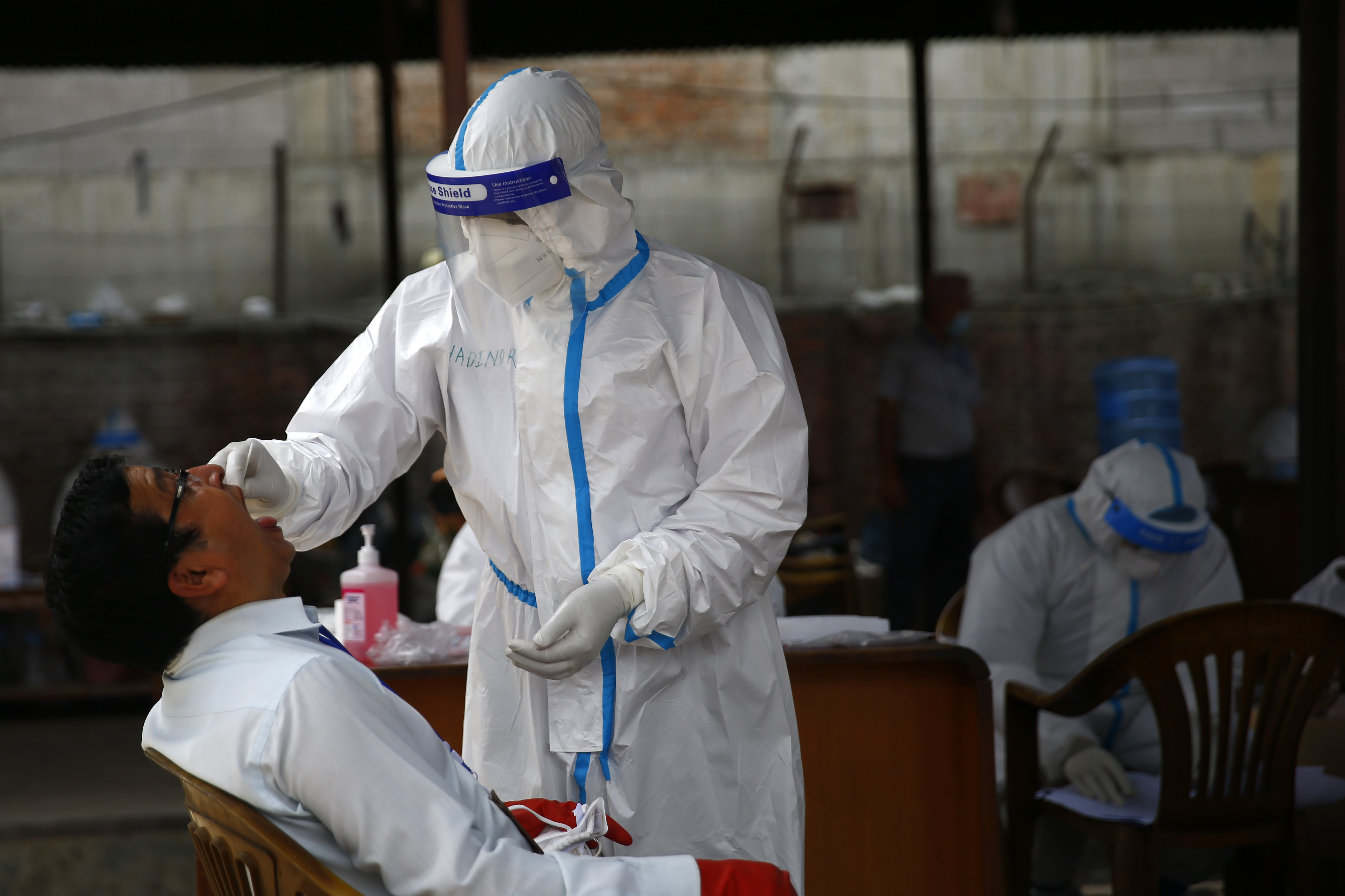 A health worker takes the sample of a person for Polymerase Chain Reaction (PCR) test to detect COVID-19, at a fruit and vegetable market, as a preventive measure againt the spread of coronavirus, during a government-imposed nationwide lockdown, in Kathmandu, on Thursday, May 14, 2020. Photo: Skanda Guatam/THT