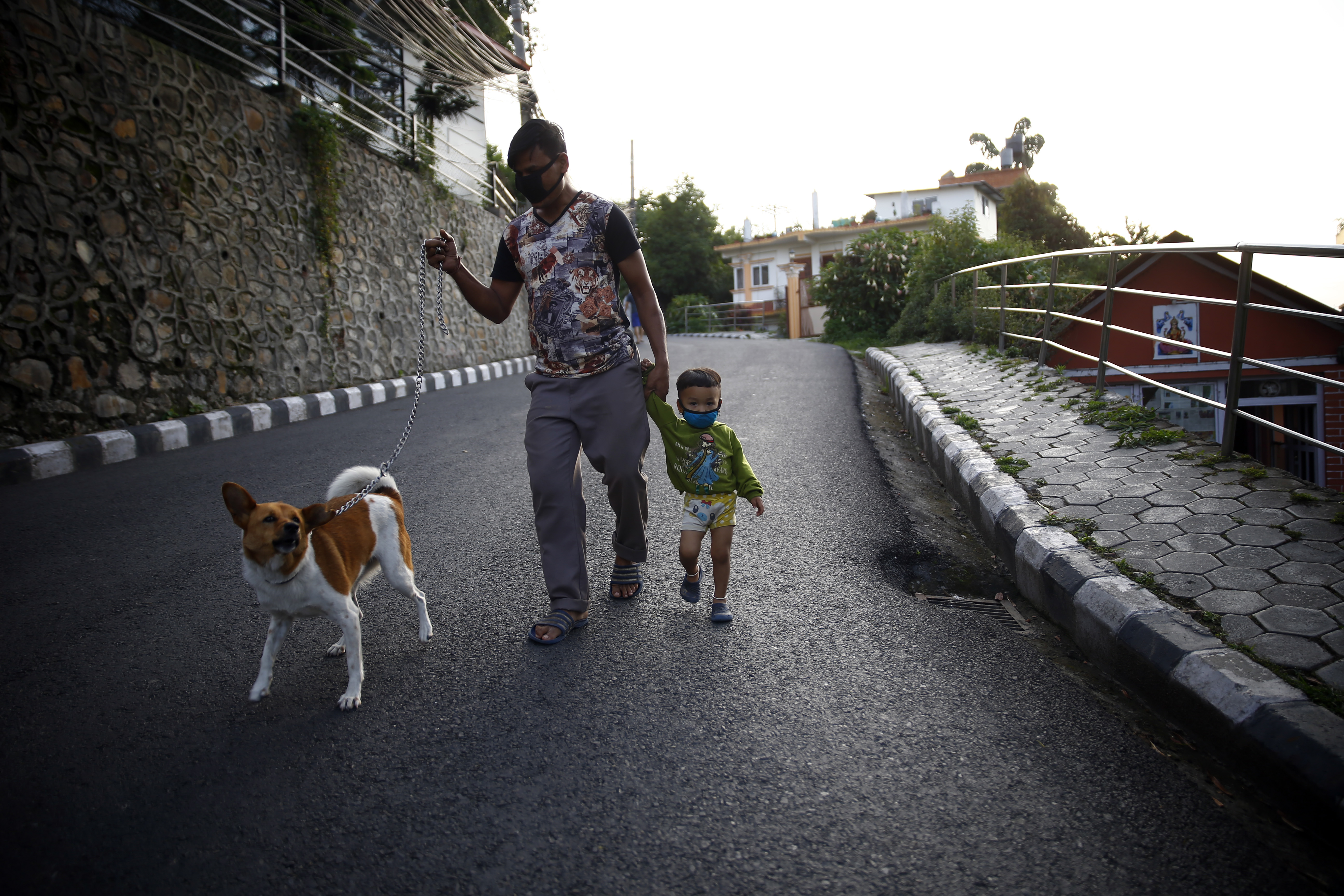 A father-son duo and their pet stroll around the neighborhood during the COVID-19 lockdown, in Lalitpur, on Saturday, May 30, 2020. Photo: Skanda Gautam/THT