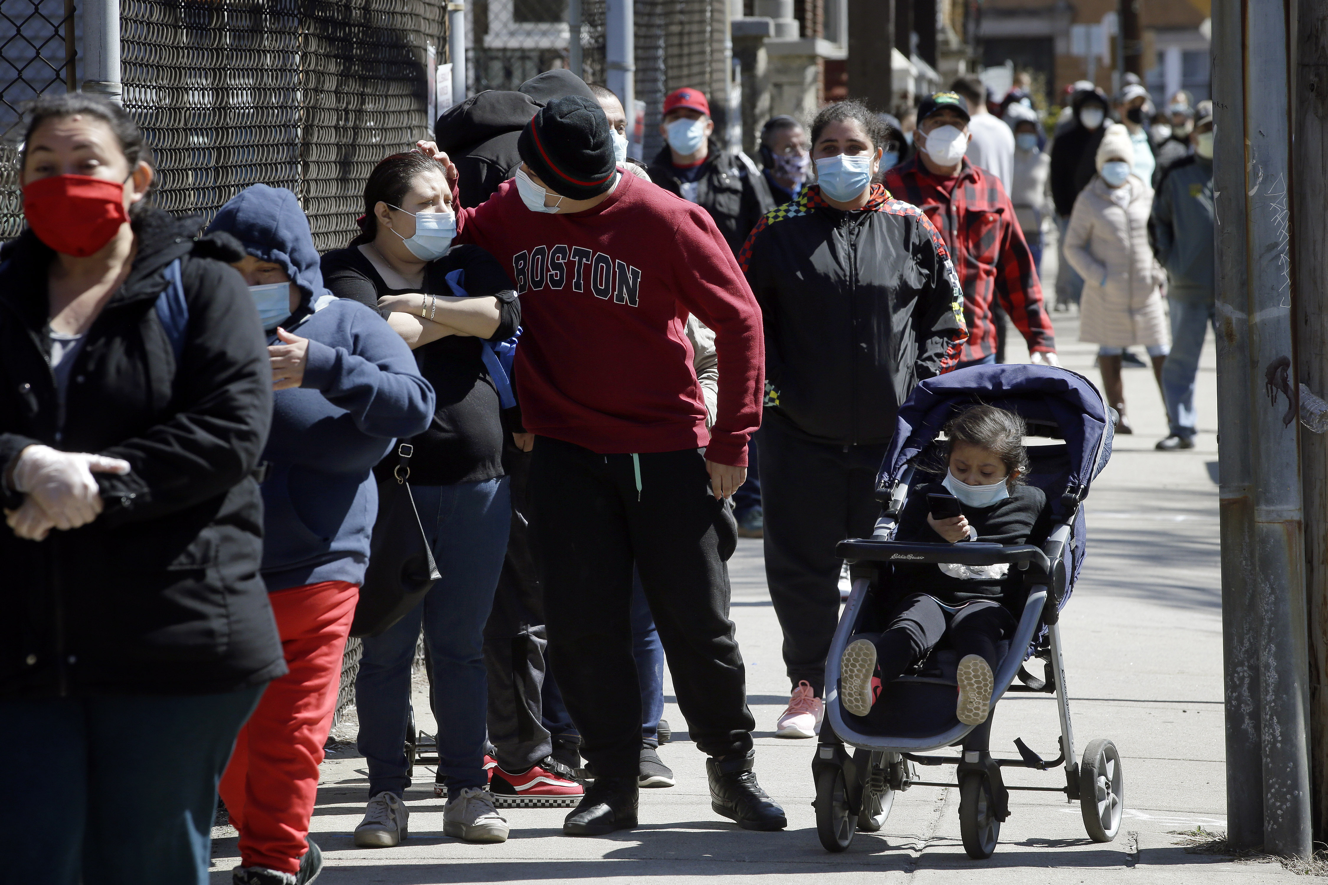 People wear masks out of concern for the coronavirus while standing in line outside a Salvation Army food pantry, Tuesday, May 5, 2020, in Chelsea, Mass. (AP Photo/Steven Senne)