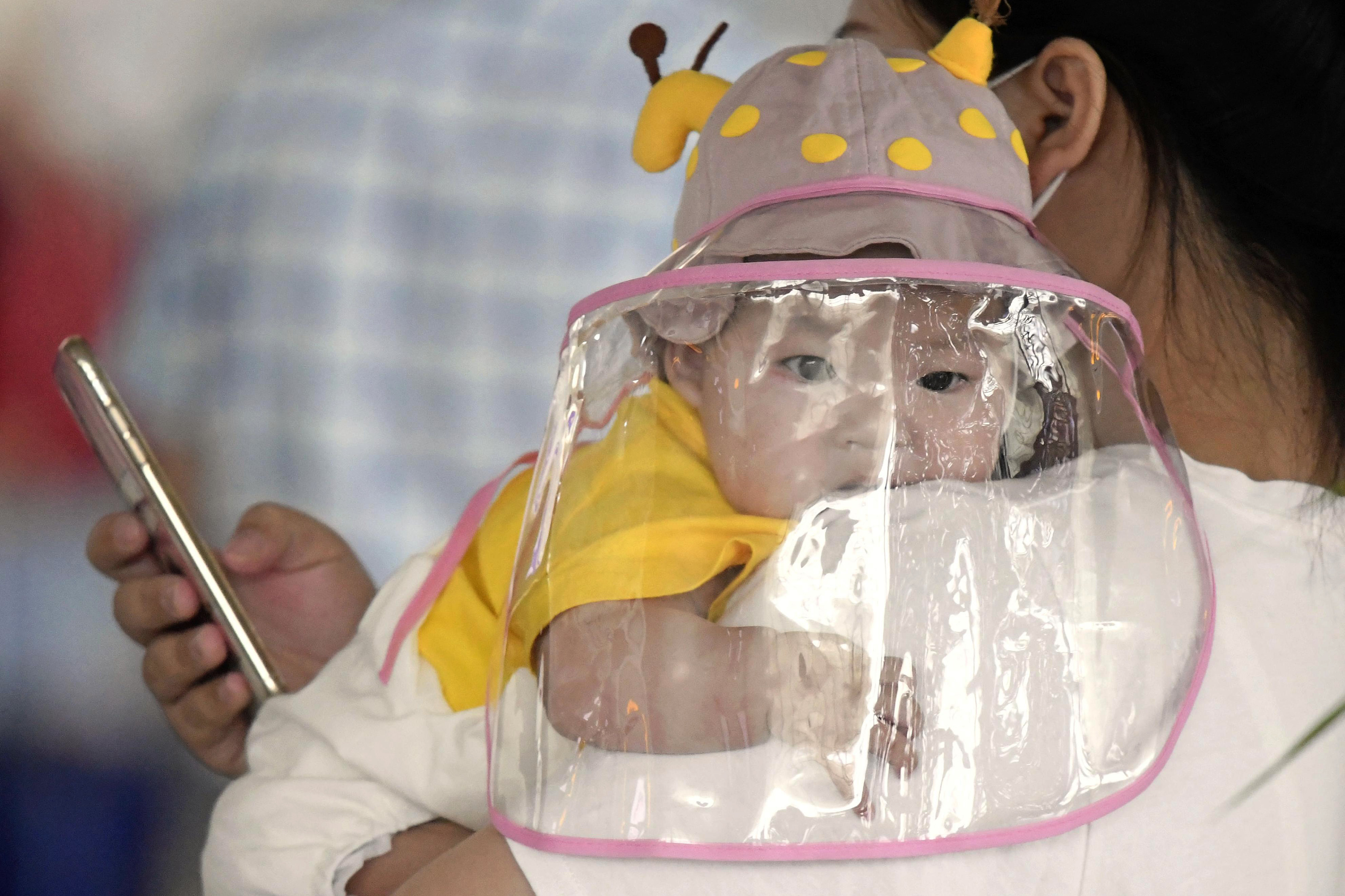 A baby with a face shield waits to board a plane at an airport in Wuhan, central China's Hubei Province Saturday, May 23, 2020. China on Saturday reported no new confirmed cases or deaths from the new coronavirus. Photo: AP