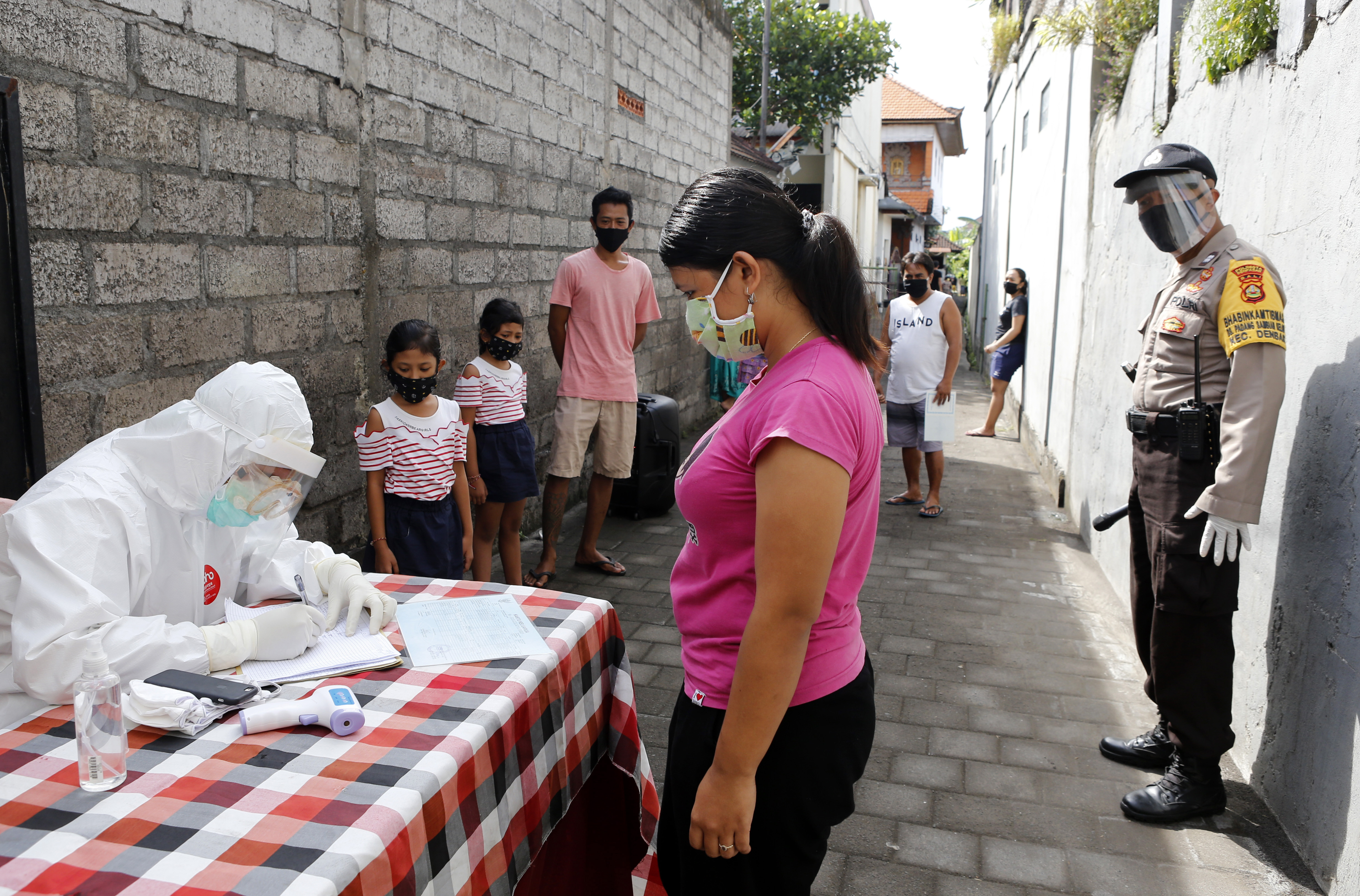 A heath worker checks ID of residents as they queue to receive a coronavirus antibody test at a village in Bali, Indonesia, Wednesday, May 27, 2020. Photo:AP