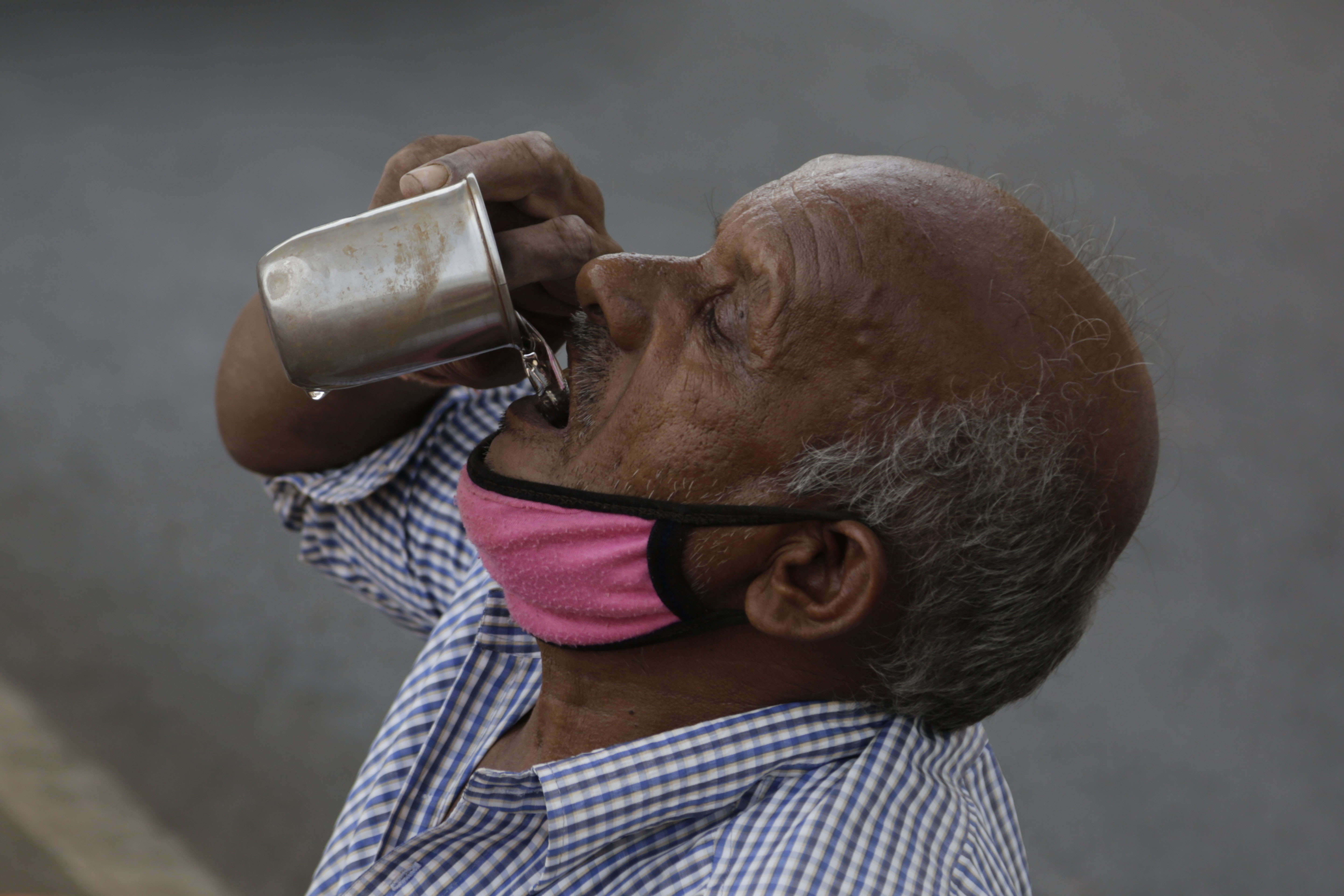 An Indian man selling earthen pots beneath a bridge drinks water in Ahmedabad, India, Thursday, May 28, 2020. India faced scorching temperatures and the worst locust invasion in decades on Thursday as authorities prepared for the end of a months-long coronavirus lockdown despite recording thousands of new infections every day. (AP Photo/Ajit Solanki)