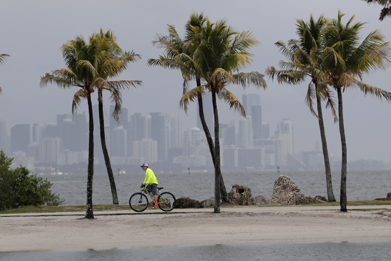 The Miami skyline is shrouded in clouds as a cyclist rides along Biscayne Bay at Matheson Hammock Park, in Miami, May 15, 2020. Photo: AP/File