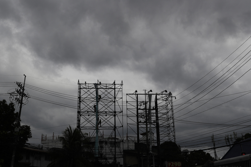 Dark clouds envelop the skies as workers fold a billboard to prepare for the coming of typhoon Vongfong in Manila, Philippines Thursday May, 14, 2020. Photo: AP