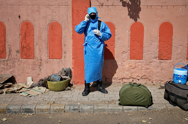 A man wearing protective gear speaks on his mobile phone as he waits for transport upon his arrival from New Delhi outside a railway station, after a limited reopening of India's giant rail network following a nearly seven-week lockdown to slow the spreading of the coronavirus disease (COVID-19), in Ahmedabad, India, May 14, 2020. Photo: Reuters