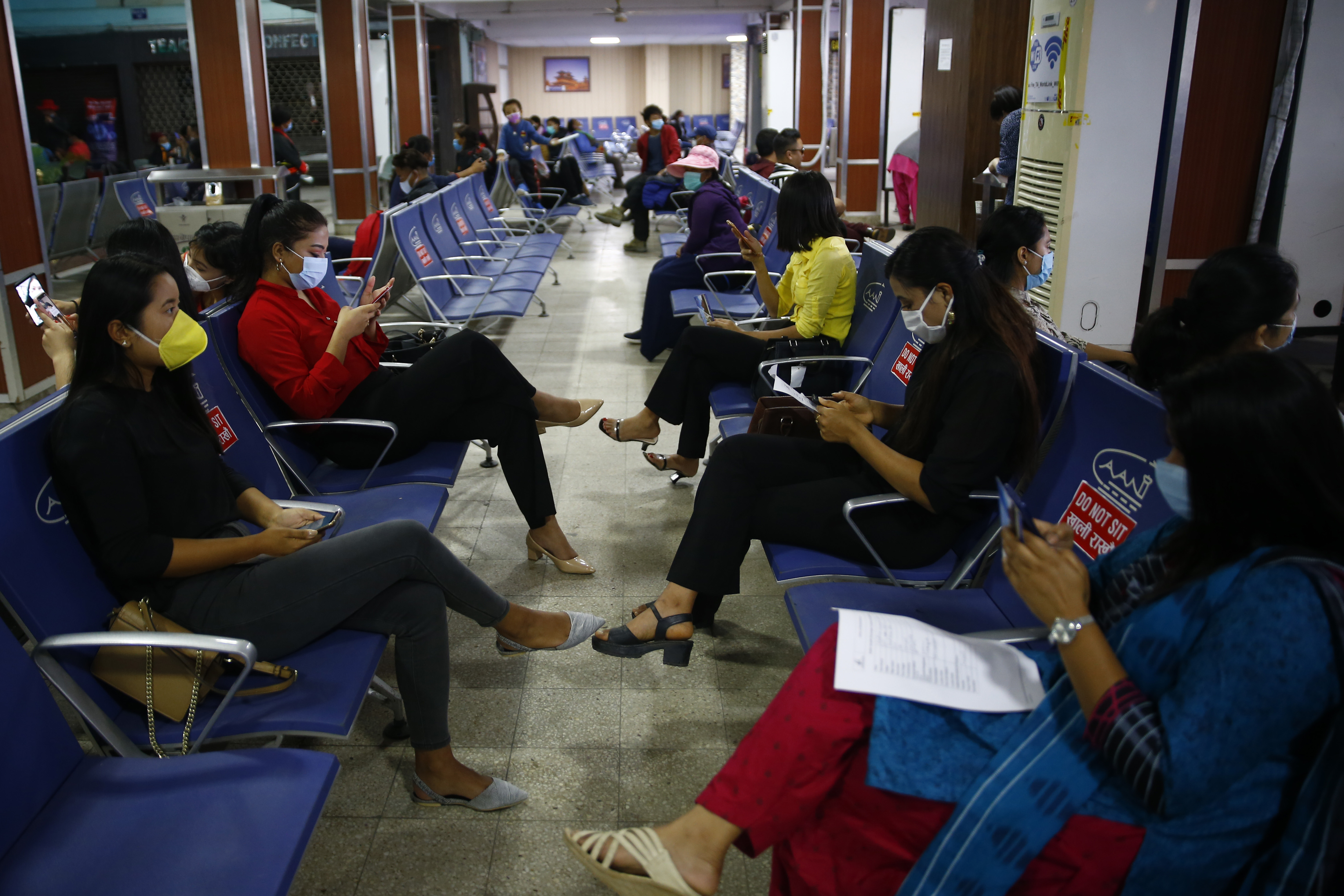 Passengers of Buddha Air sit wait to board their flights during a mock drill to make necessary preparations for the resumption of domestic and international flights starting August 1 as Nepal has suspended all passenger flights enforcing the lockdown to contain the spread of coronavirus disease at Tribhuvan International Airport in Kathmandu, Nepal on Thursday, June 25, 2020.