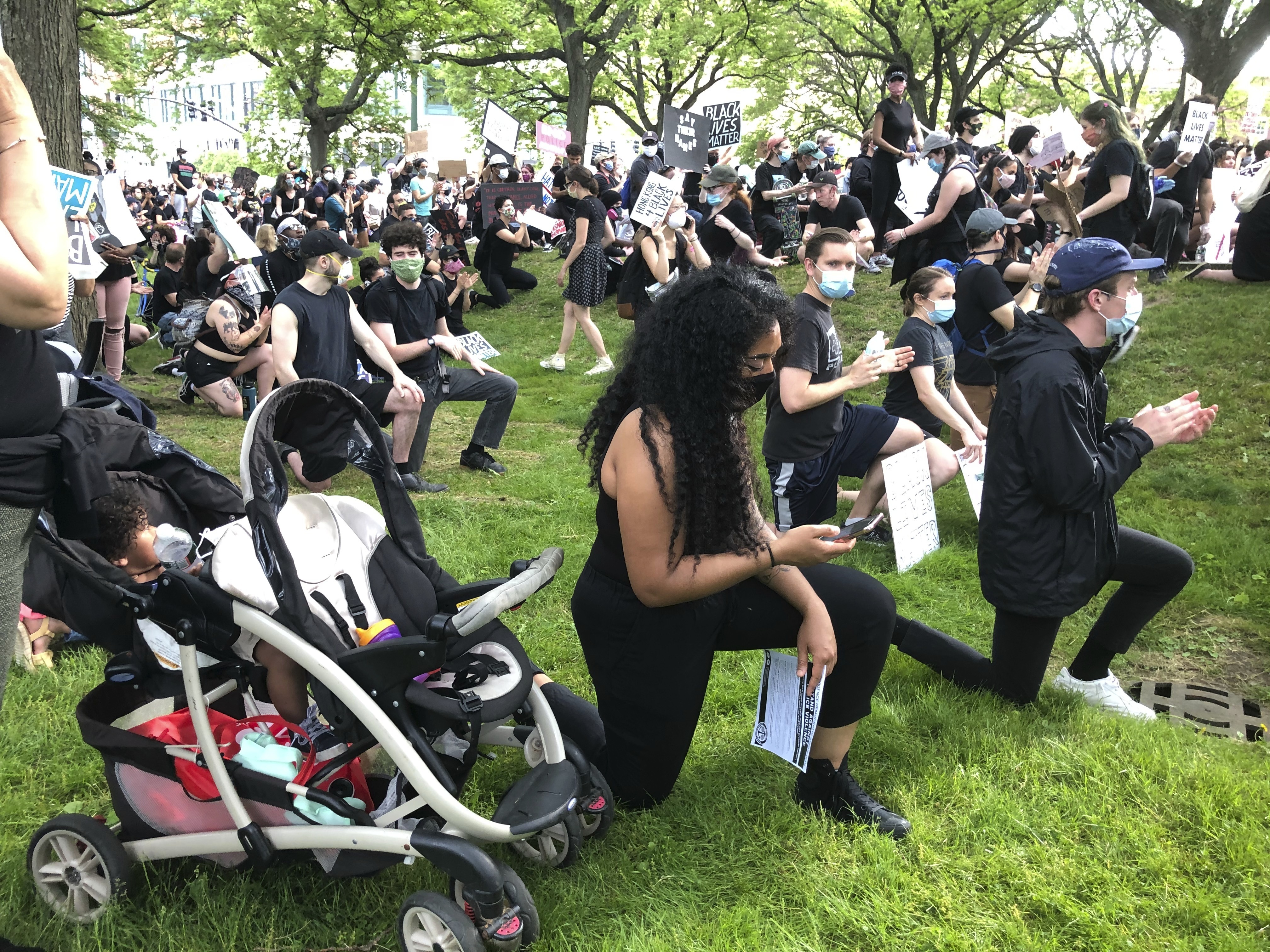 Anjel Newmann, 32, kneels while scanning her phone during a peaceful rally in Providence, R.I. on Friday, June 5. Newmann said sheu2019s mostly using Instagram and Facebook to organize protests while people younger than her are using Snapchat. Photo: AP