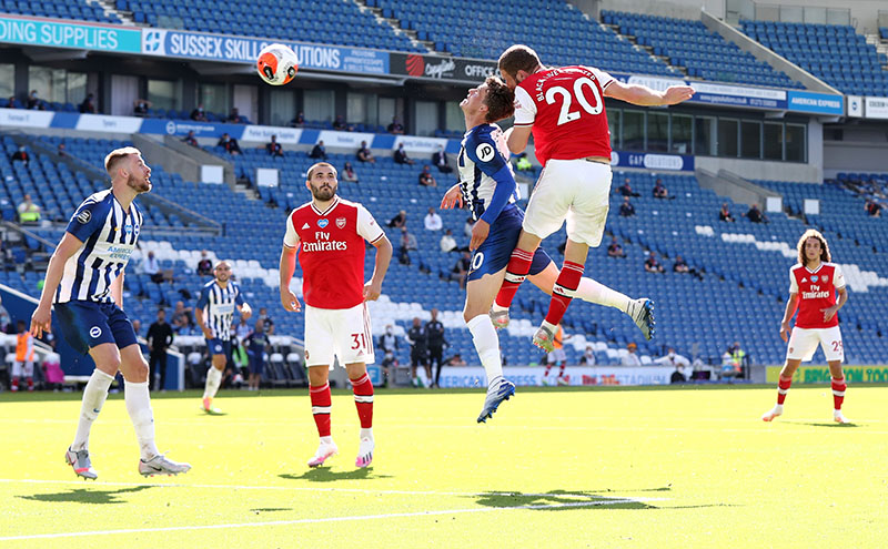 Arsenal's Shkodran Mustafi heads at goal under a challenge from Brighton &amp; Hove Albion's Solly March as play resumes behind closed doors following the outbreak of the coronavirus disease (COVID-19) during the Premier League match between Brighton &amp; Hove Albion and Arsenal, at The American Express Community Stadium, in Brighton, Britain, on June 20, 2020. Photo: Gareth Fuller/Pool via Reuters