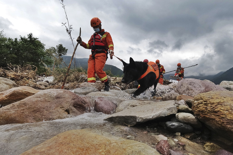 Rescue workers and a rescue dog search for victims in the aftermath of flooding in Yihai Town of Mianning County in southwestern China's Sichuan Province on Sunday, June 28, 2020. Photo: Wang Yun/Xinhua via AP