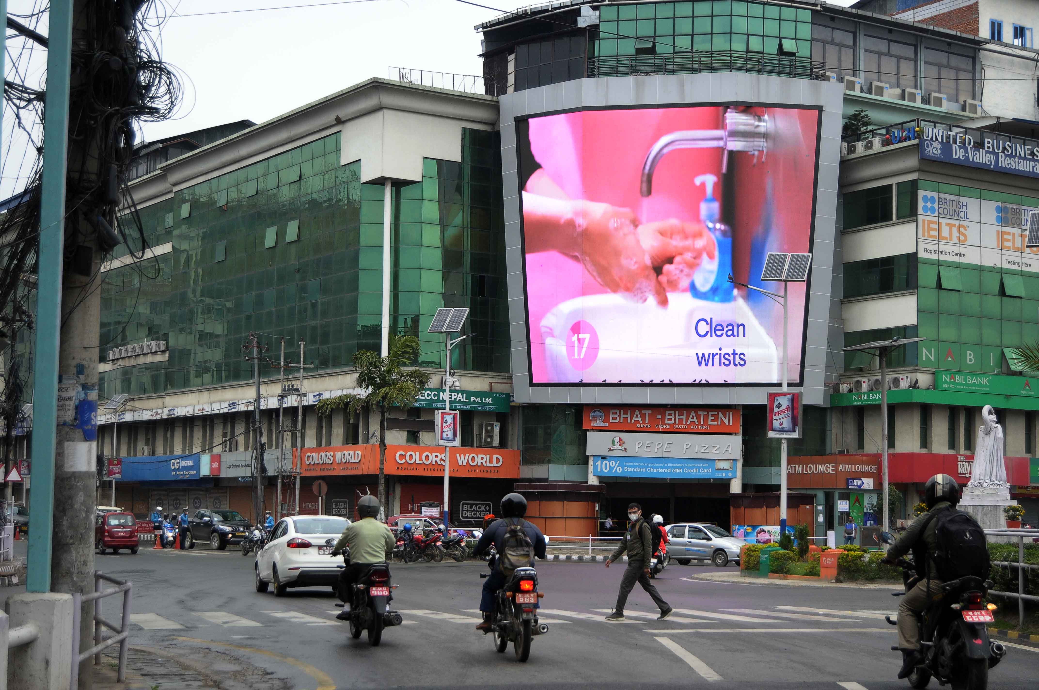 A TV showing awareness of procedures for sanitizing hands in the fight against COVID-19 to be watched by a passerby in Tripureshwor, Kathmandu, on Tuesday. PHOTO: BALKRISHNA THAPA CHHETRI