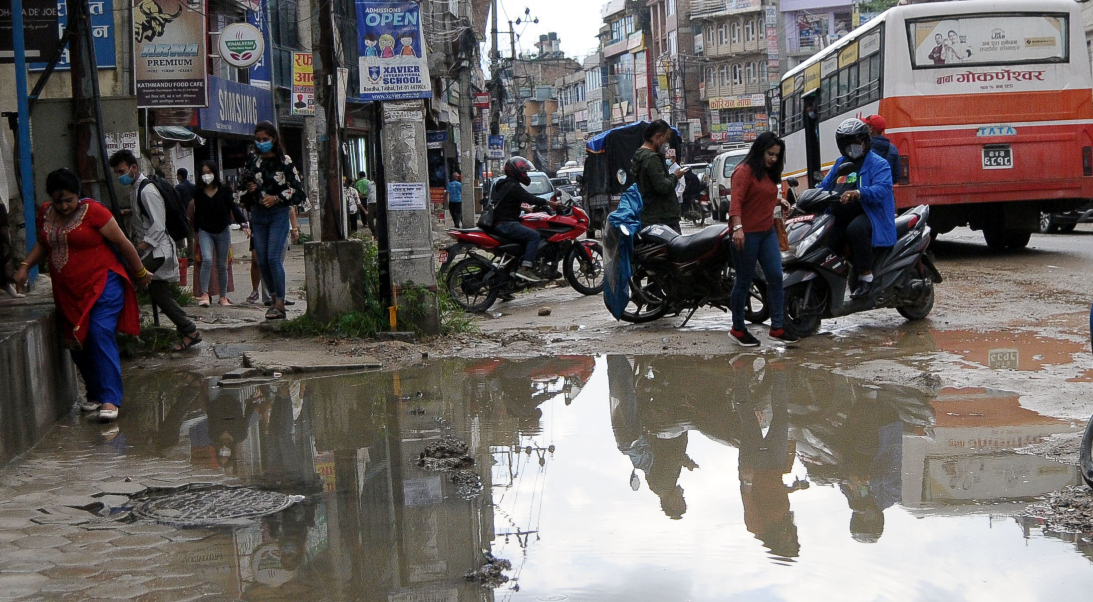 Pedestrians navigate their way through a puddle as they walk along Chabahil--Jorpati road section, in Kathmandu, on Friday, July 31, 2020. Photo: Balkrishna Thapa/THT